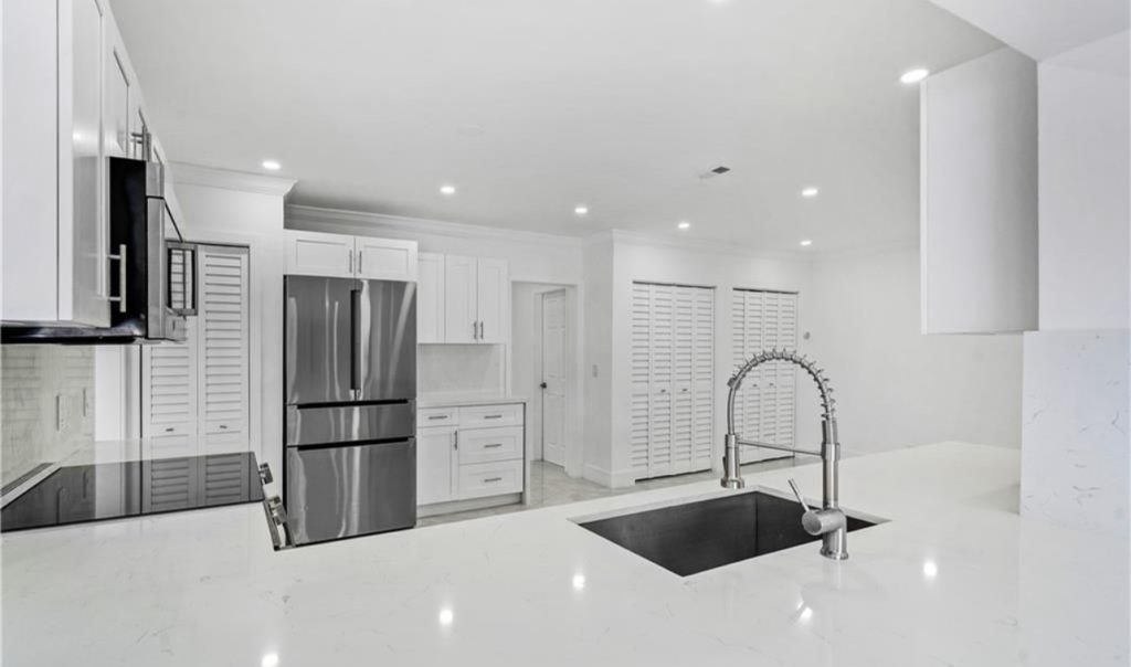 Remodeled kitchen in Miami, full view, including all white fixtures, walls, and ceilings. 